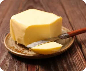 ナイフでひとかけらを切ったバターの写真